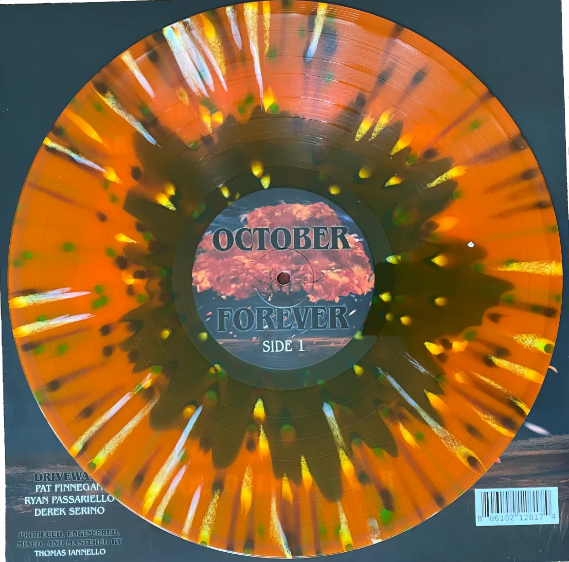 photo showing driveways October forever orange blue splatter vinyl pressing, side 1, sitting on top of the album's cardboard sleeve. UPC 806102128174.